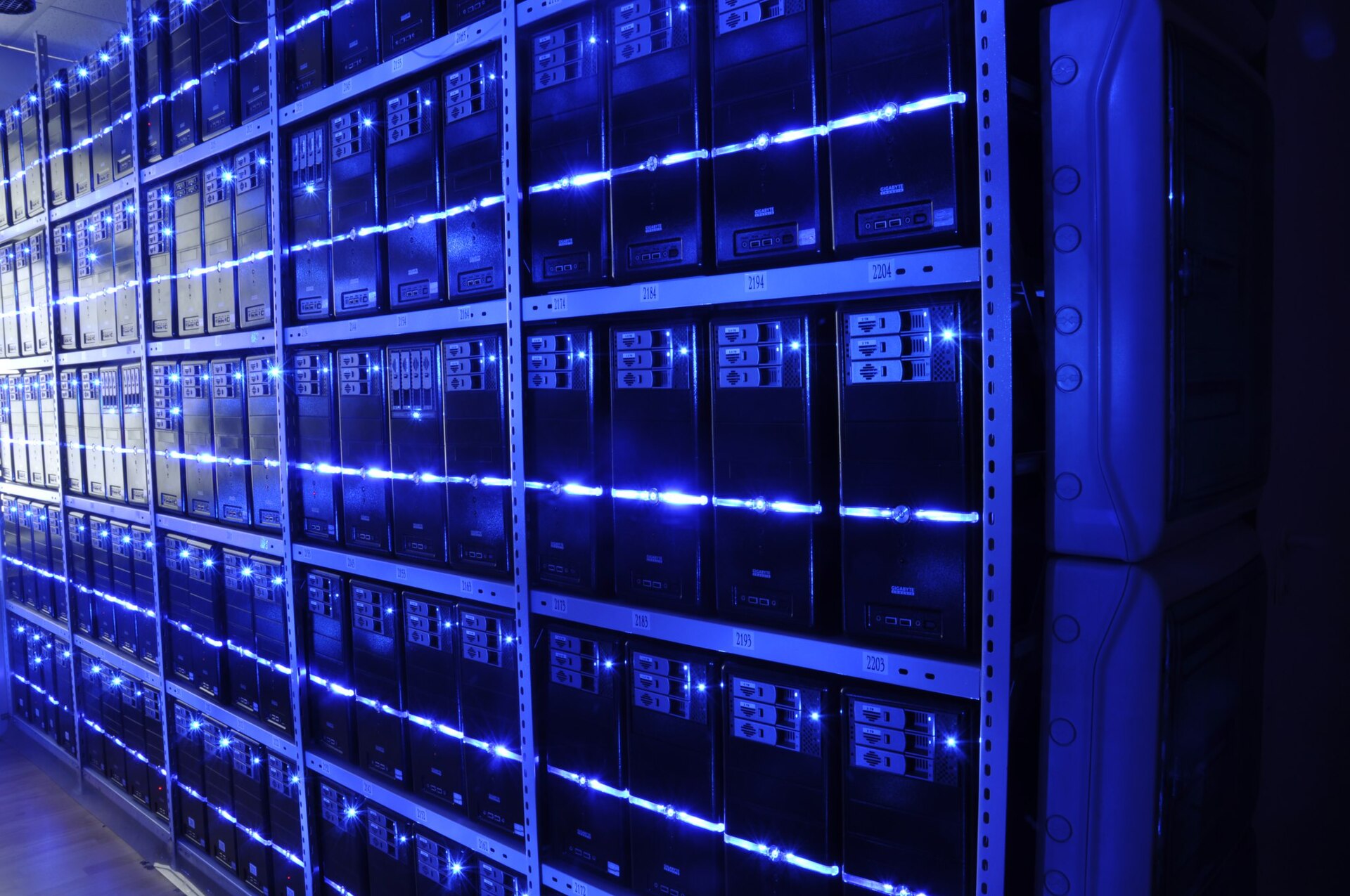 Rows of servers on shelving in a data center, lit with blue LED strips