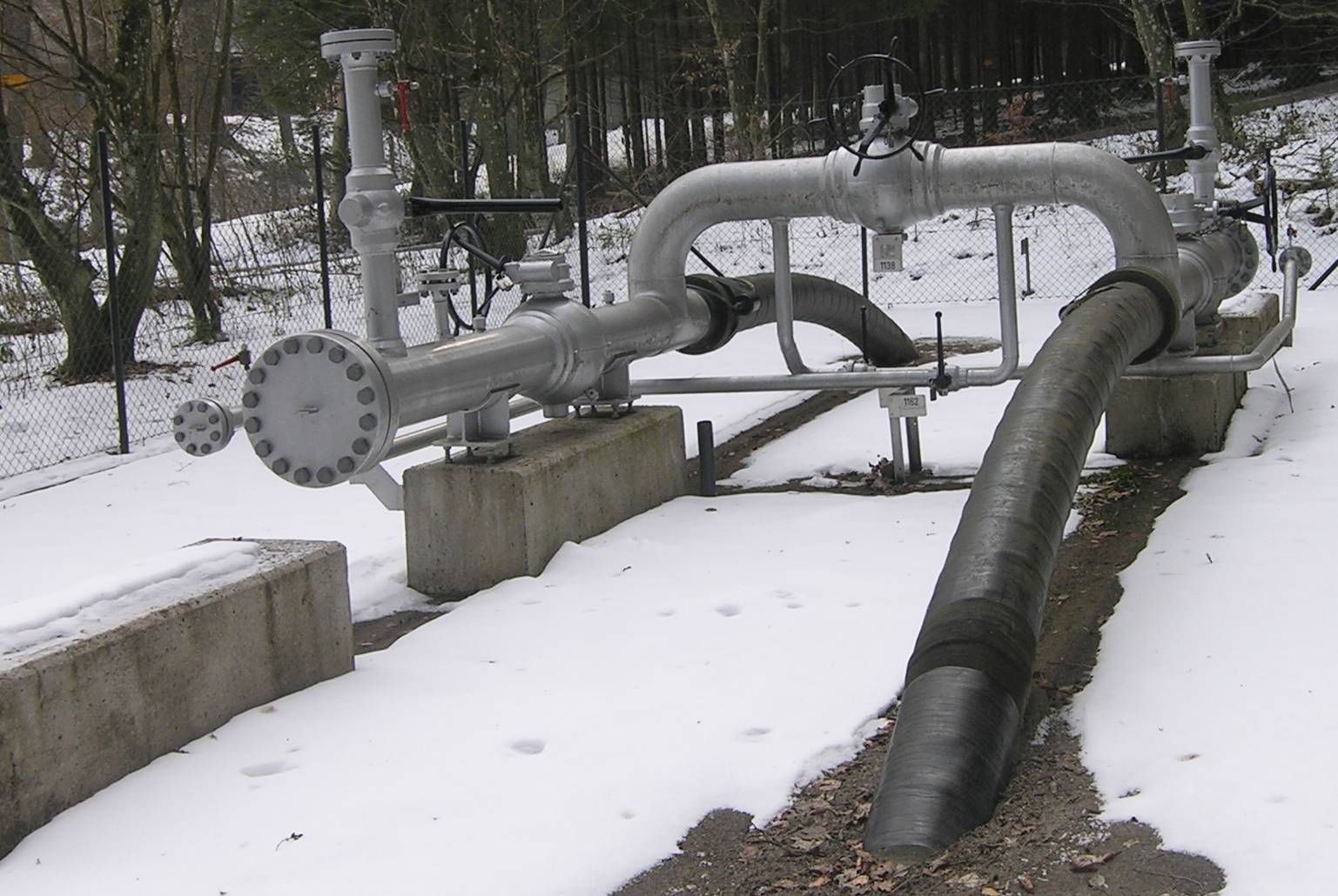 A small brick valve house beside a pipeline running across open farmland