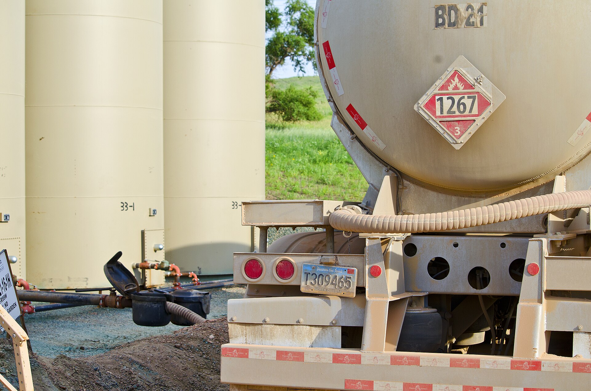An oil truck beside storage equipment at a tank site