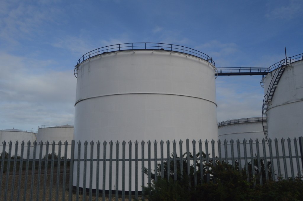 Oil storage tanks seen across open ground, with pipework and walkways at the base