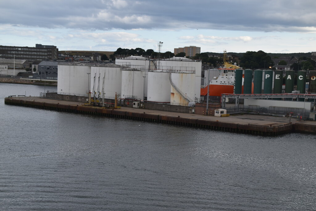 Oil storage tanks seen across open ground with pipework at the base