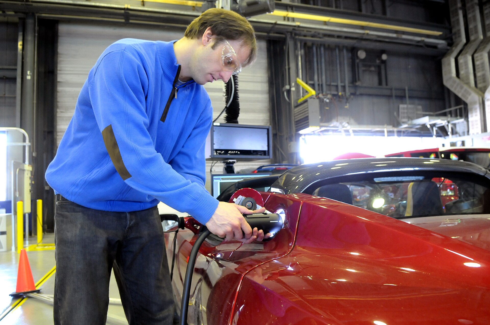 A technician preparing a car for crash and endurance testing in a laboratory