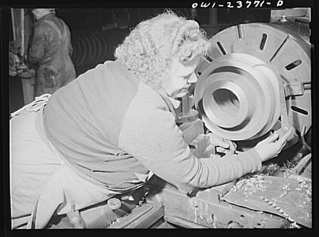 A machinist measuring part of a locomotive wheel with calipers in a railroad shop