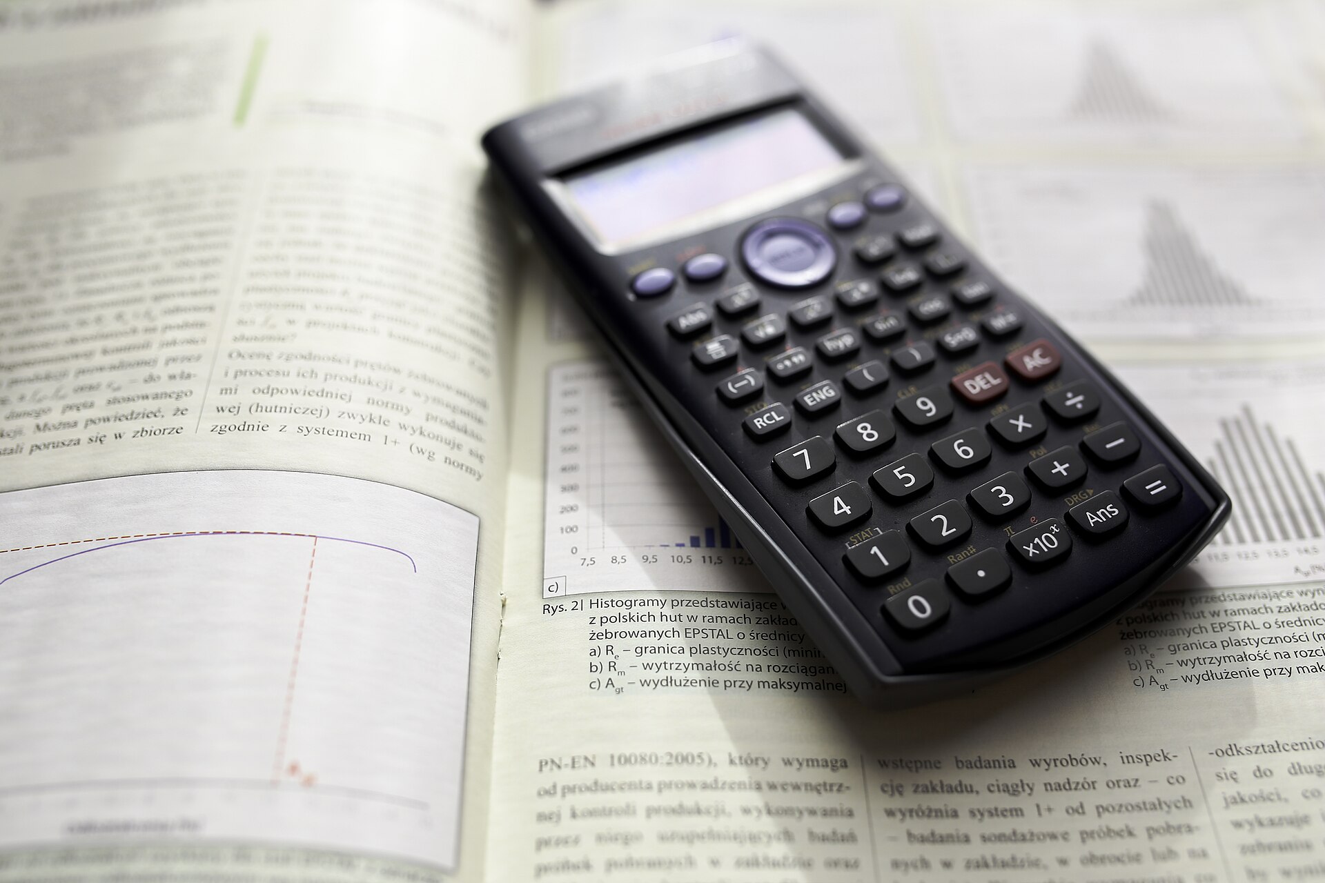 A scientific calculator lying on a desk, keys and display in view