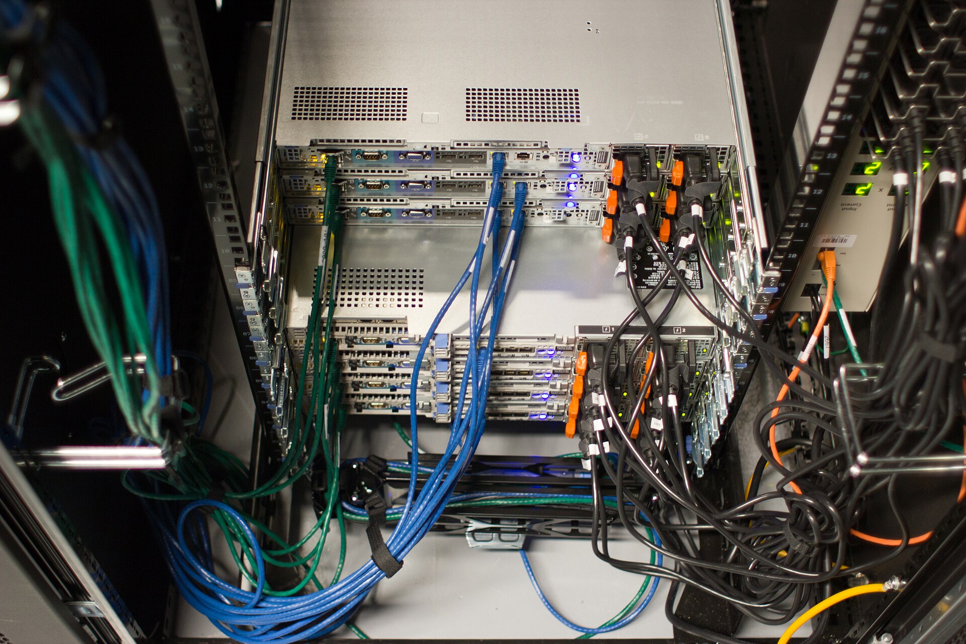 Rack servers with blue network cables and black power cords seen from behind