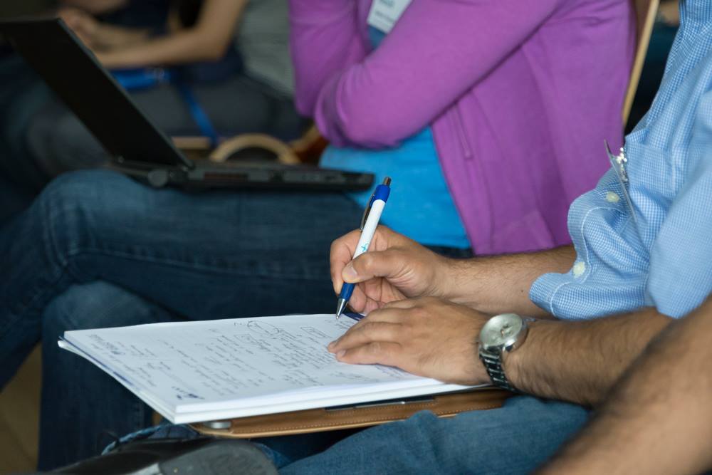 Close-up of a person writing notes by hand on a notepad with a pen
