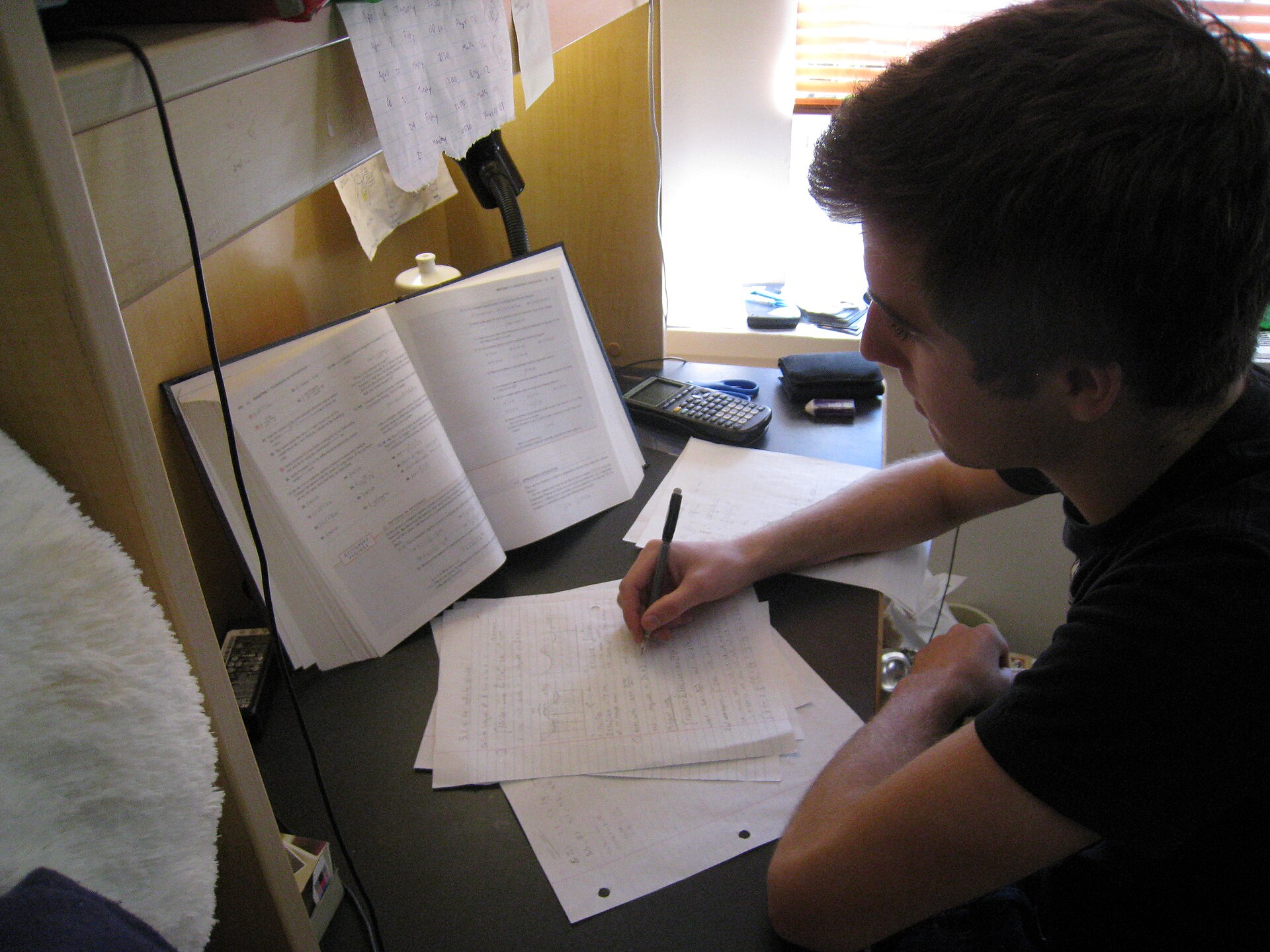 A student studying with notes and books at a desk