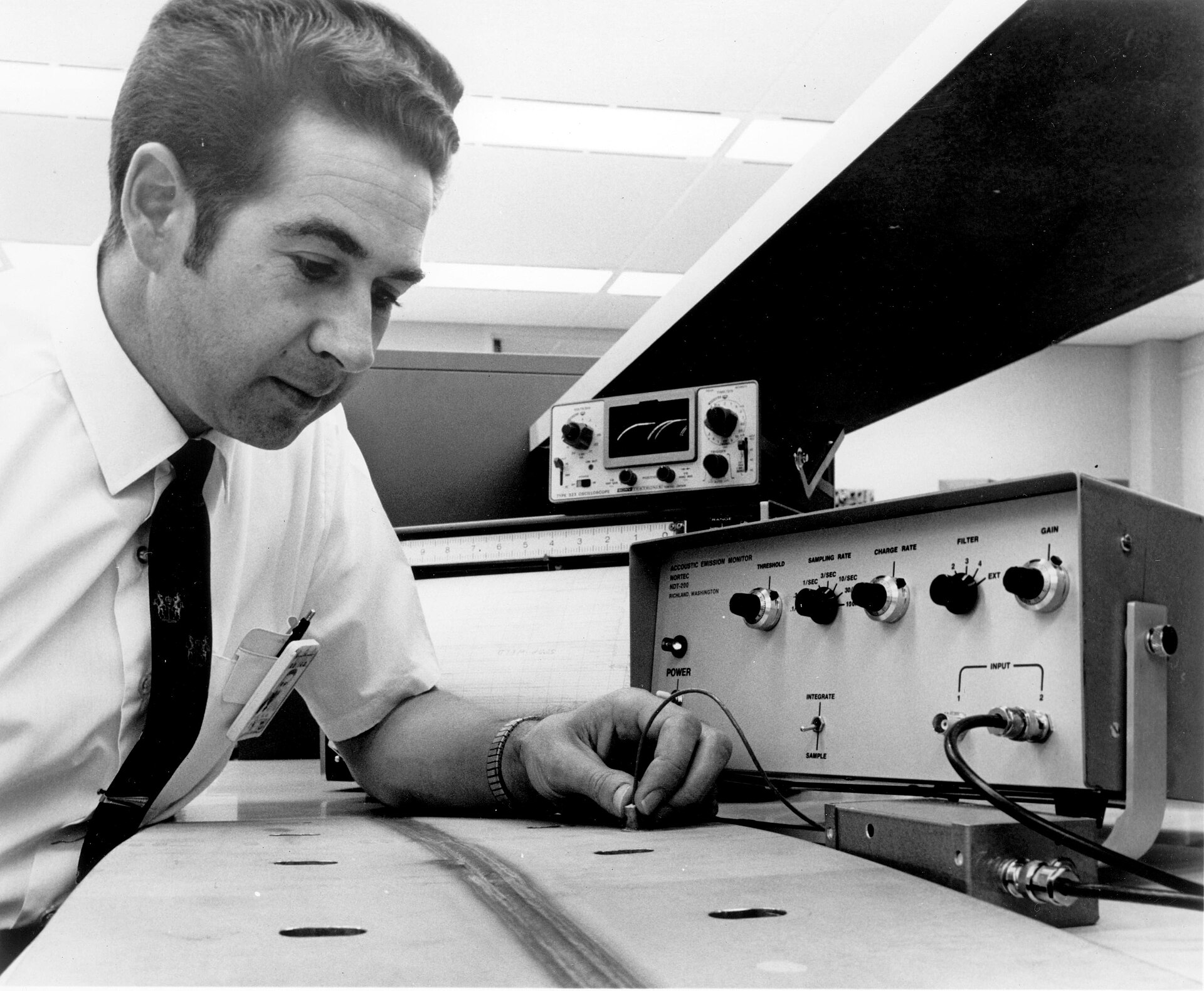A technician holding an ultrasonic probe against a metal component during a test