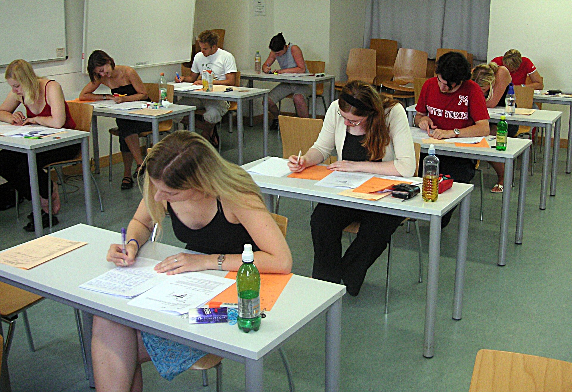Candidates writing at separate desks during a written exam